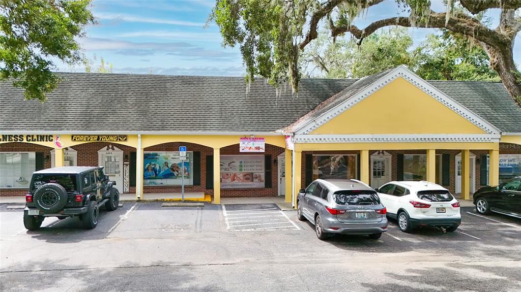 A single-story commercial building with yellow accents, a covered walkway, and a paved parking lot — 110 LITHIA PINECREST ROAD UNIT D, BRANDON, FL