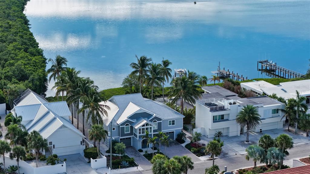 An aerial view shows three waterfront houses with palm trees and private docks — 340 MORNINGSIDE DRIVE, SARASOTA, FL