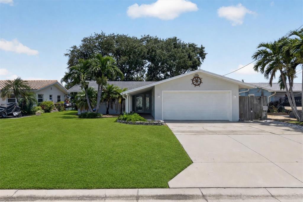 A single-story house with a white garage door, a front lawn, and palm trees — 541 LILLIAN DRIVE, MADEIRA BEACH, FL
