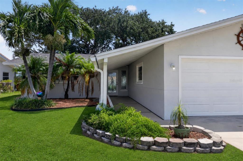 A single-story house with a white garage, a covered entryway, and a landscaped front yard — 541 LILLIAN DRIVE, MADEIRA BEACH, FL