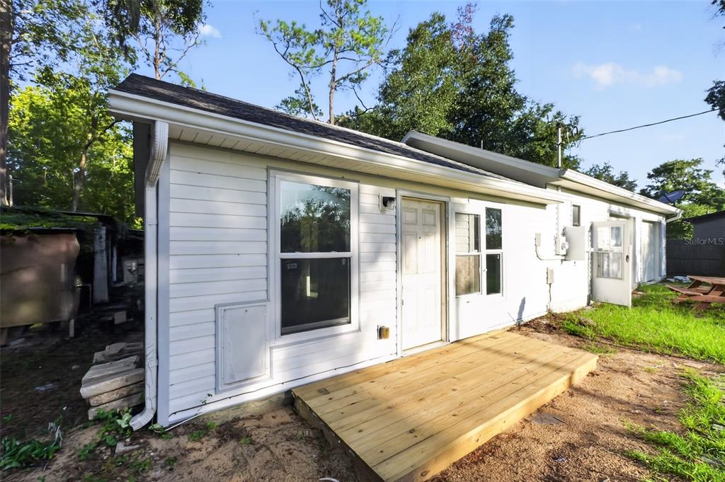 The exterior of a white-sided house features a wooden deck and a white entry door — 9314 SW 32ND TERRACE, OCALA, FL