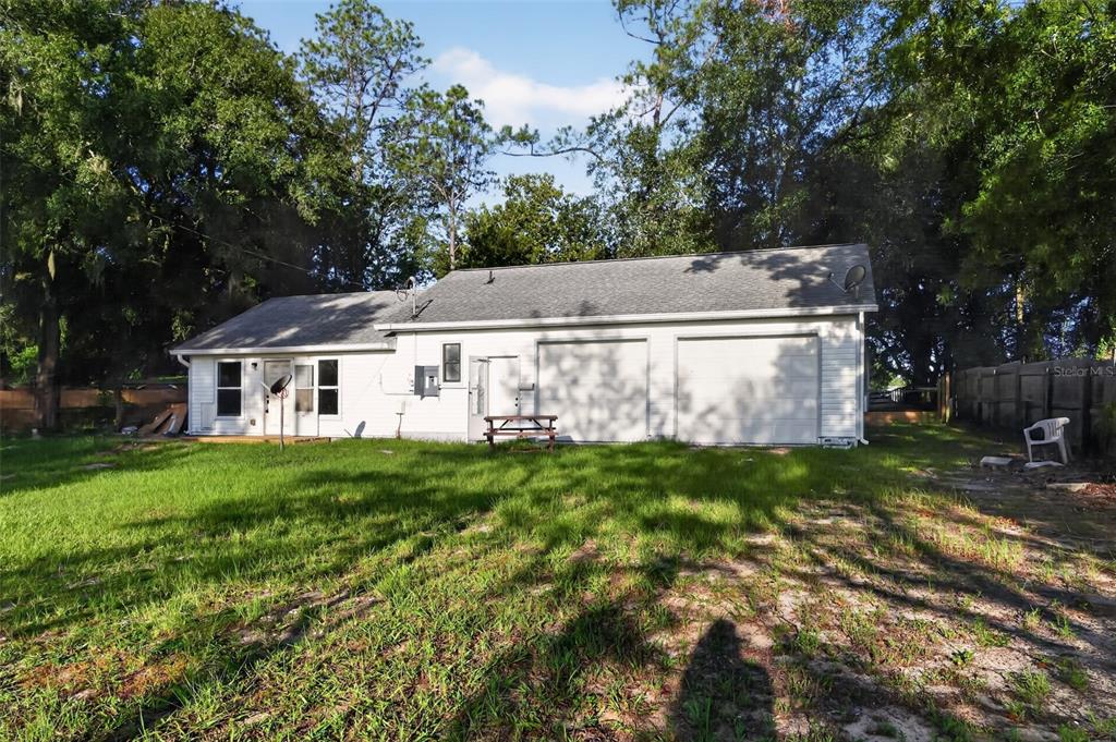 The exterior of a white house with a two-car garage and a grassy backyard — 9314 SW 32ND TERRACE, OCALA, FL