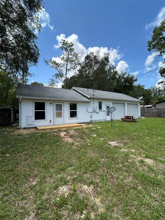 The exterior of a white, single-story house features a small wooden deck and a garage — 9314 SW 32ND TERRACE, OCALA, FL