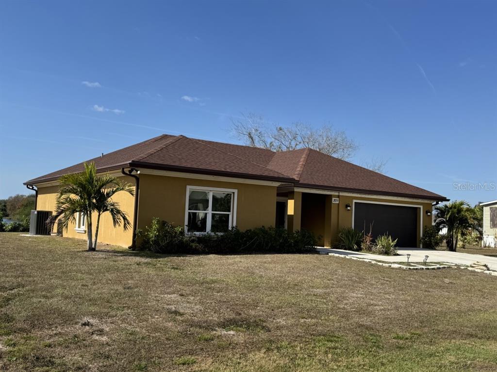 A single-story house with a brown hip roof, tan stucco exterior, and a two-car garage — 2809 SE 27TH AVENUE, OKEECHOBEE, FL