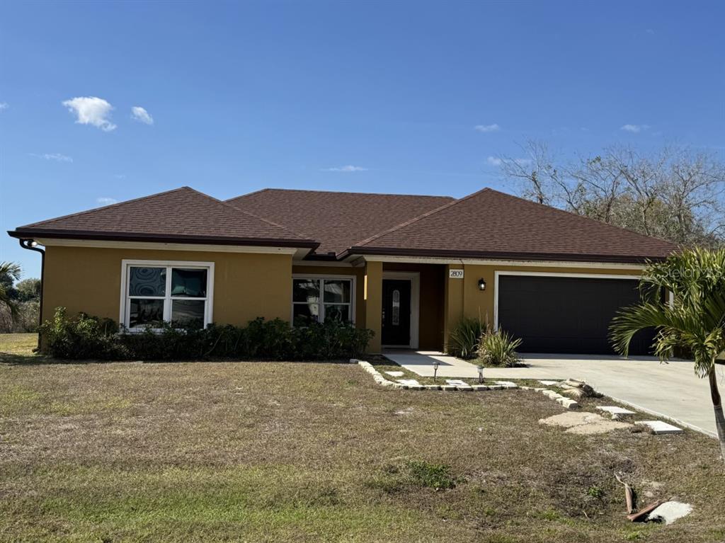 A single-story house with a brown roof, tan stucco exterior, and a two-car garage — 2809 SE 27TH AVENUE, OKEECHOBEE, FL