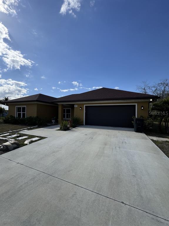 A single-story house with a large concrete driveway and a dark two-car garage — 2809 SE 27TH AVENUE, OKEECHOBEE, FL