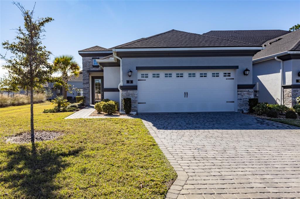 A gray single-story house with a white garage door and a stone-accented exterior — 3 NEWHAVEN LANE, ORMOND BEACH, FL