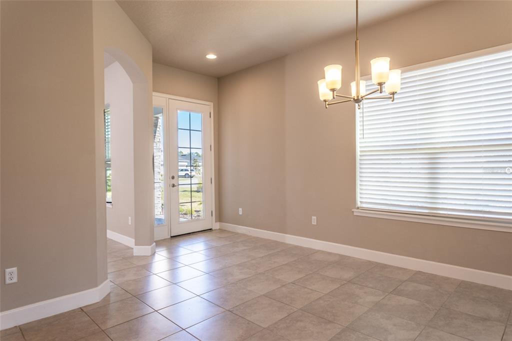 A dining area with tile flooring, a chandelier, and a glass-paneled door leading outside — 3 NEWHAVEN LANE, ORMOND BEACH, FL