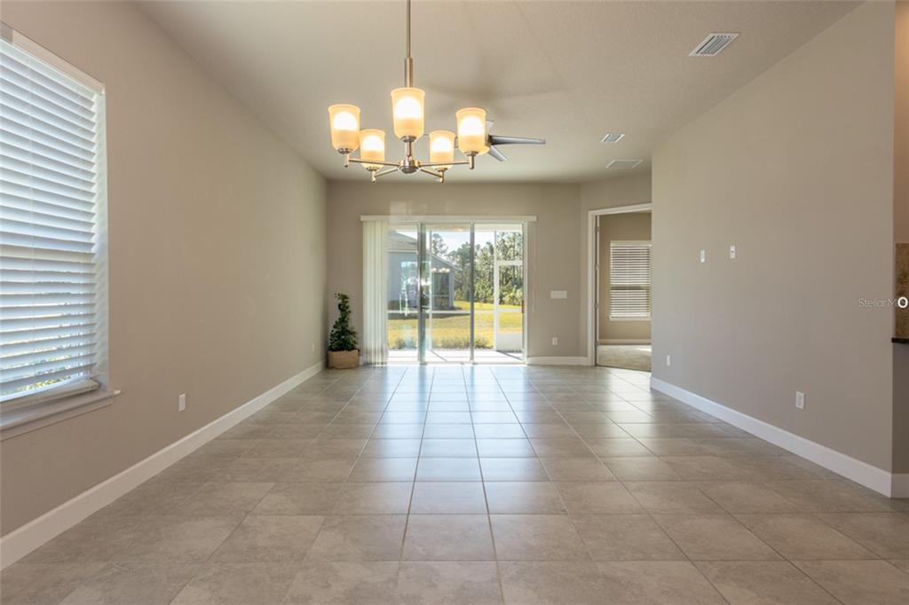 A dining area features tile flooring, a chandelier, and sliding glass doors leading to a patio — 3 NEWHAVEN LANE, ORMOND BEACH, FL