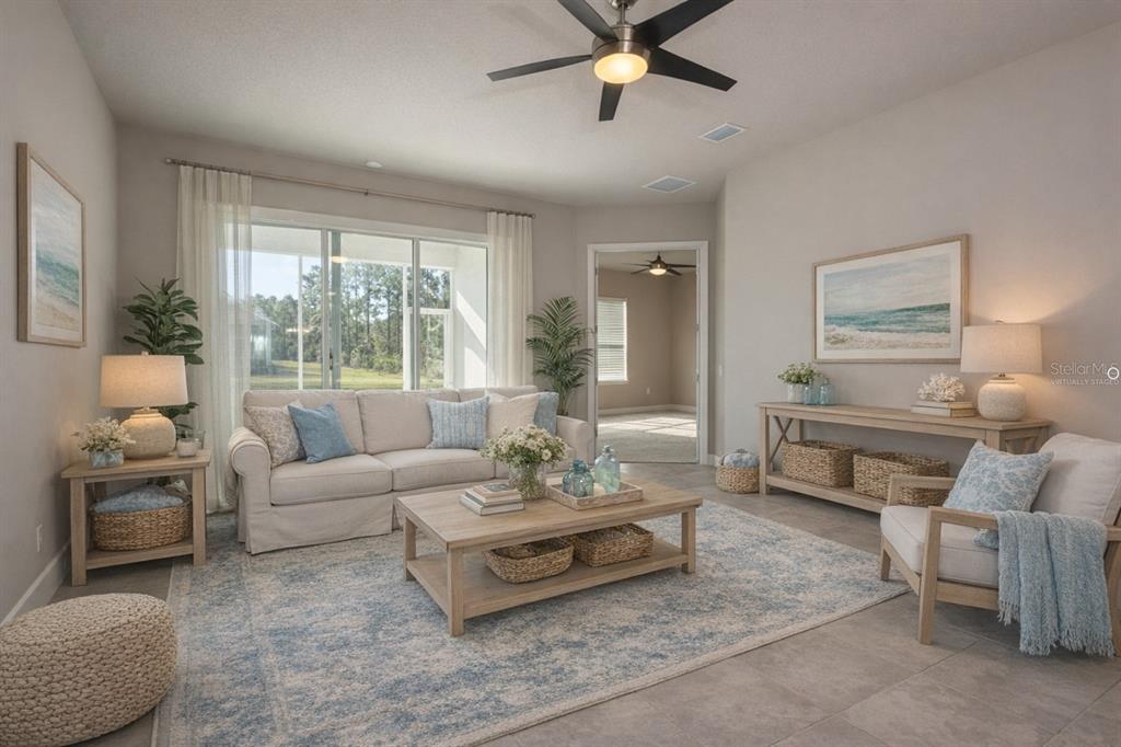 A living room with a sofa, coffee table, armchair, and large windows overlooking a yard — 3 NEWHAVEN LANE, ORMOND BEACH, FL