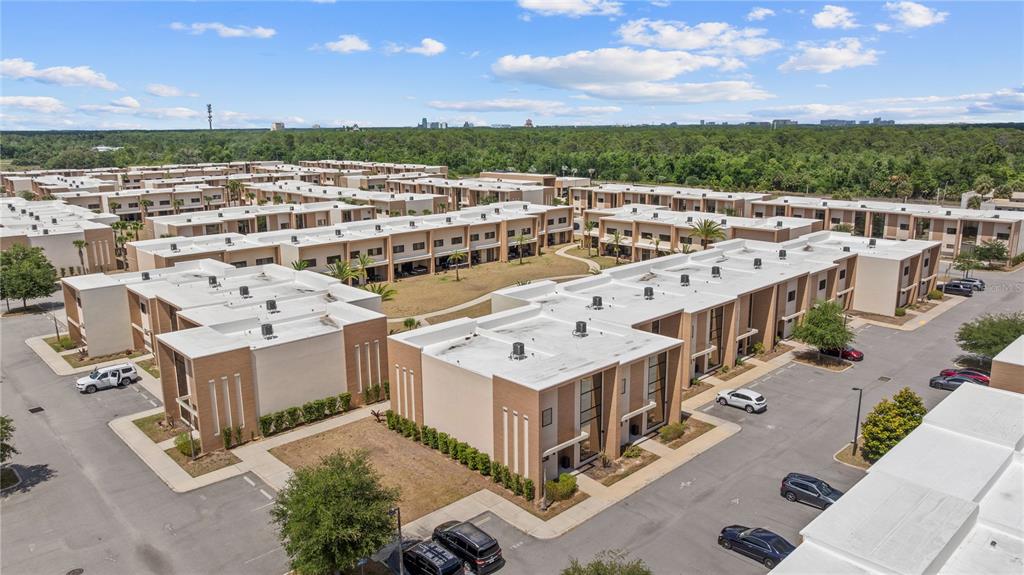 An aerial view of a multi-unit residential complex with flat roofs and paved parking lots — 7526 BROOKLYN DRIVE, KISSIMMEE, FL