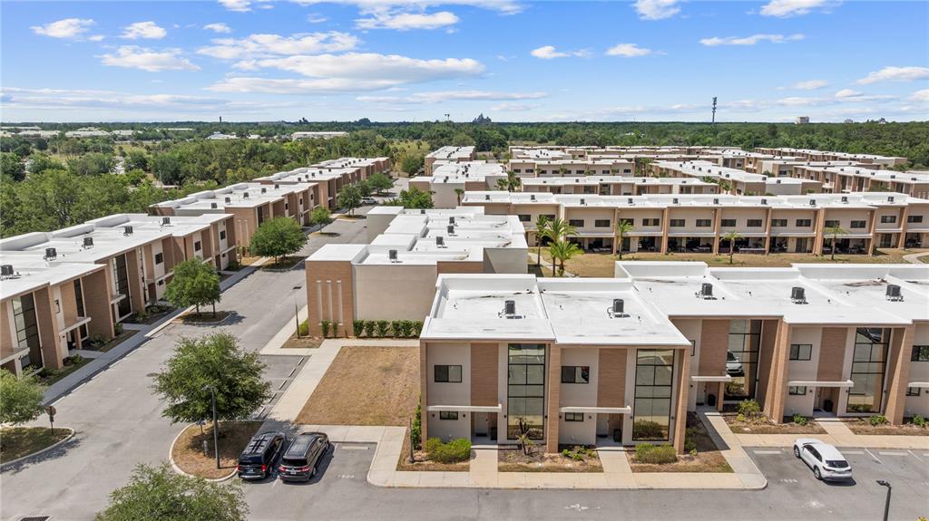 An aerial view shows multiple rows of modern townhomes with flat roofs and paved parking — 7526 BROOKLYN DRIVE, KISSIMMEE, FL