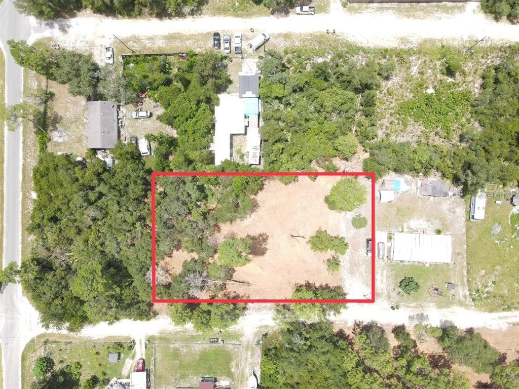 An aerial view shows a rectangular, partially cleared lot surrounded by trees and neighboring properties — W PINE STREET, PAISLEY, FL