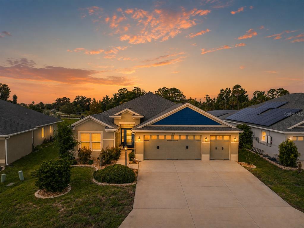 An exterior view of a single-story house with a three-car garage and a blue gable — 1078 MAYNARD PATH, THE VILLAGES, FL