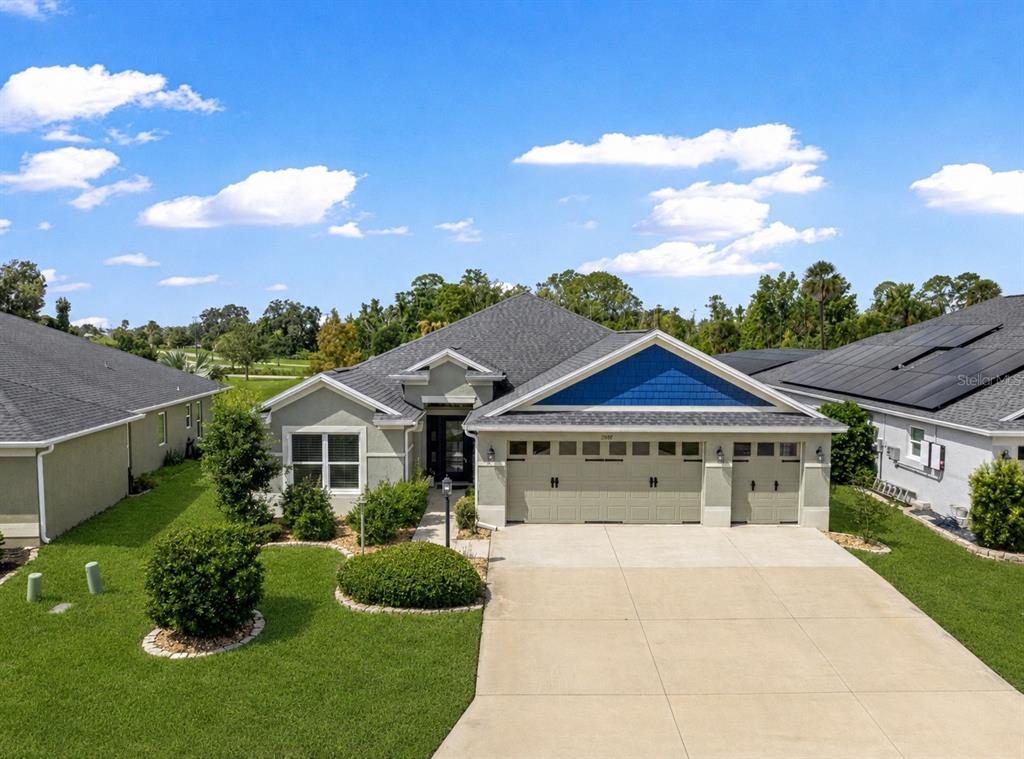 A single-story house with a three-car garage, light-colored stucco exterior, and blue gable accents — 1078 MAYNARD PATH, THE VILLAGES, FL