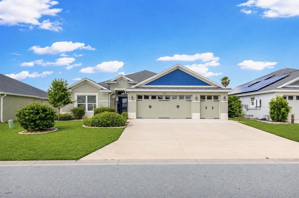 A bright blue front door with sidelights is framed by two stucco columns and planters — 1078 MAYNARD PATH, THE VILLAGES, FL