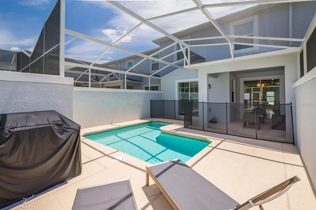 A screened-in patio features a small swimming pool, lounge chairs, and a covered seating area — 8987 BACKSWING WAY, DAVENPORT, FL