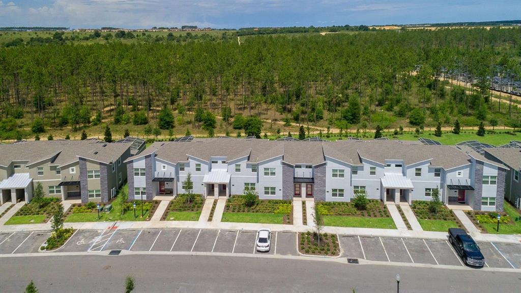 An aerial view of a multi-unit townhouse complex with a parking lot in front — 8987 BACKSWING WAY, DAVENPORT, FL