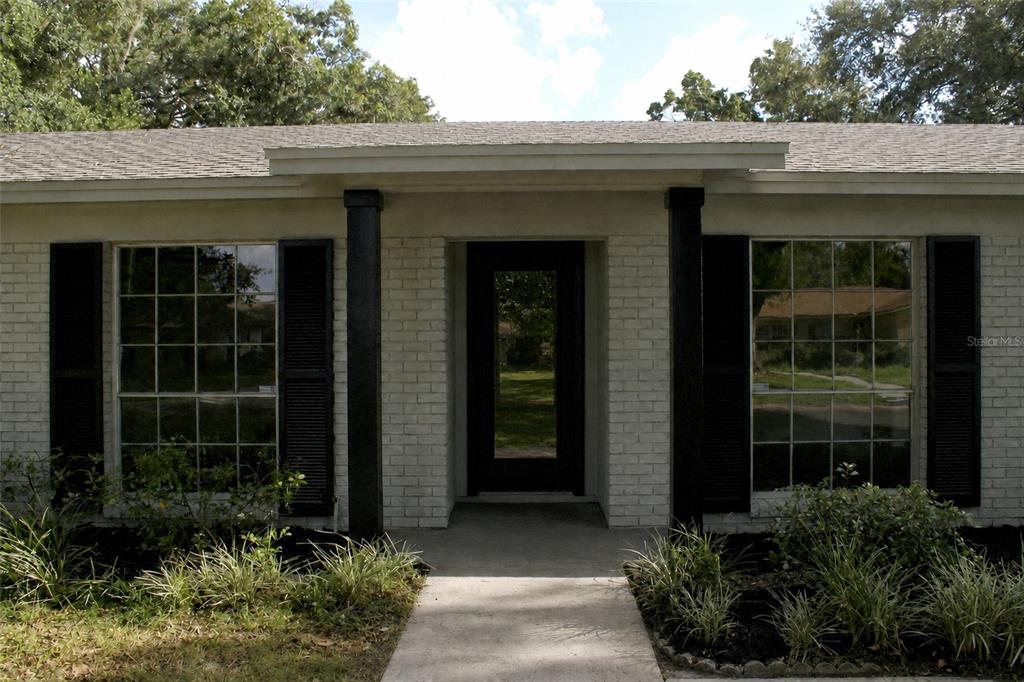 The exterior of a single-story brick house features a central entryway with black columns — 13808 CHERRY BROOK LANE, TAMPA, FL