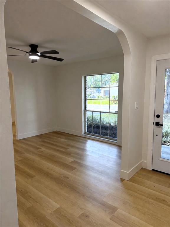 A room with light wood-look flooring, a ceiling fan, and a large window — 13808 CHERRY BROOK LANE, TAMPA, FL