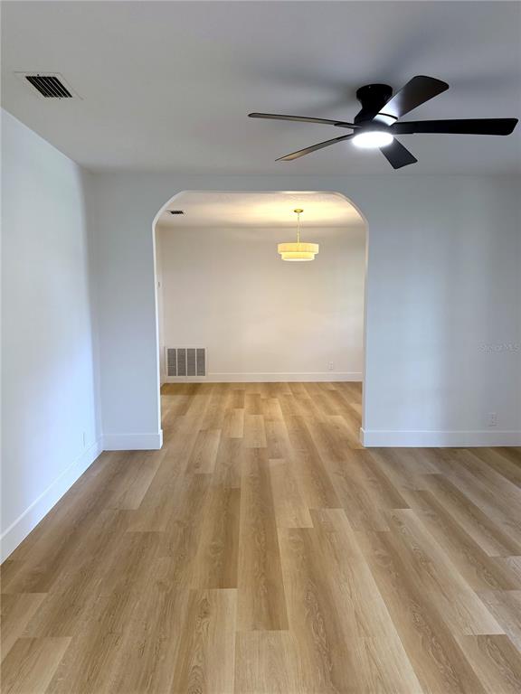 A room with light wood-look flooring and a ceiling fan leads into a dining area — 13808 CHERRY BROOK LANE, TAMPA, FL