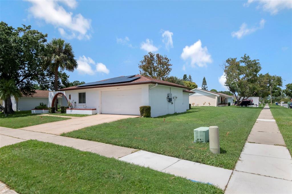 A single-story white house with a garage, solar panels, and a green lawn — 4111 105TH AVENUE N, CLEARWATER, FL