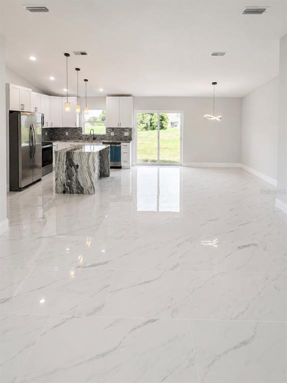 A kitchen with white cabinets, a marble-patterned island, and white tile flooring — 7016 GOLF CLUB DRIVE, SEBRING, FL