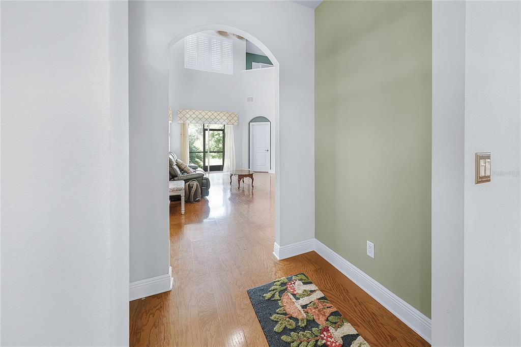 A view from a hallway into a living room with hardwood floors and arched entryways — 4961 ANNISTON CIRCLE, TAMPA, FL