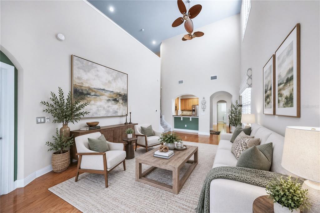 A living room with high ceilings, a blue accent wall, and neutral furniture on hardwood — 4961 ANNISTON CIRCLE, TAMPA, FL