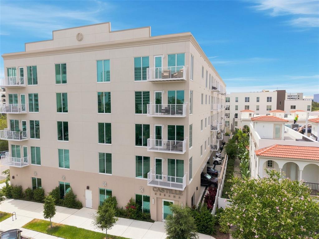 A multi-story apartment building with white balconies and large windows sits on a street corner — 600 3RD AVENUE S UNIT 302, ST PETERSBURG, FL