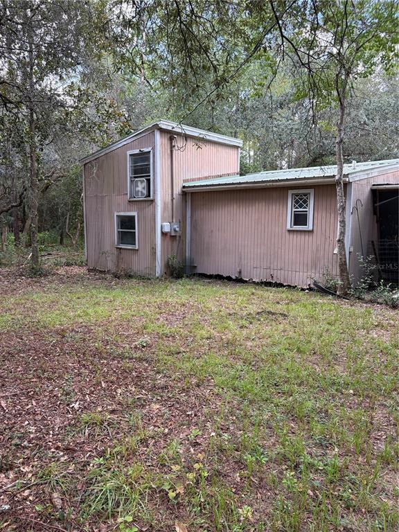 A two-story pink shed with vertical siding sits in a wooded, grassy yard — 4555 SW 175 COURT, DUNNELLON, FL