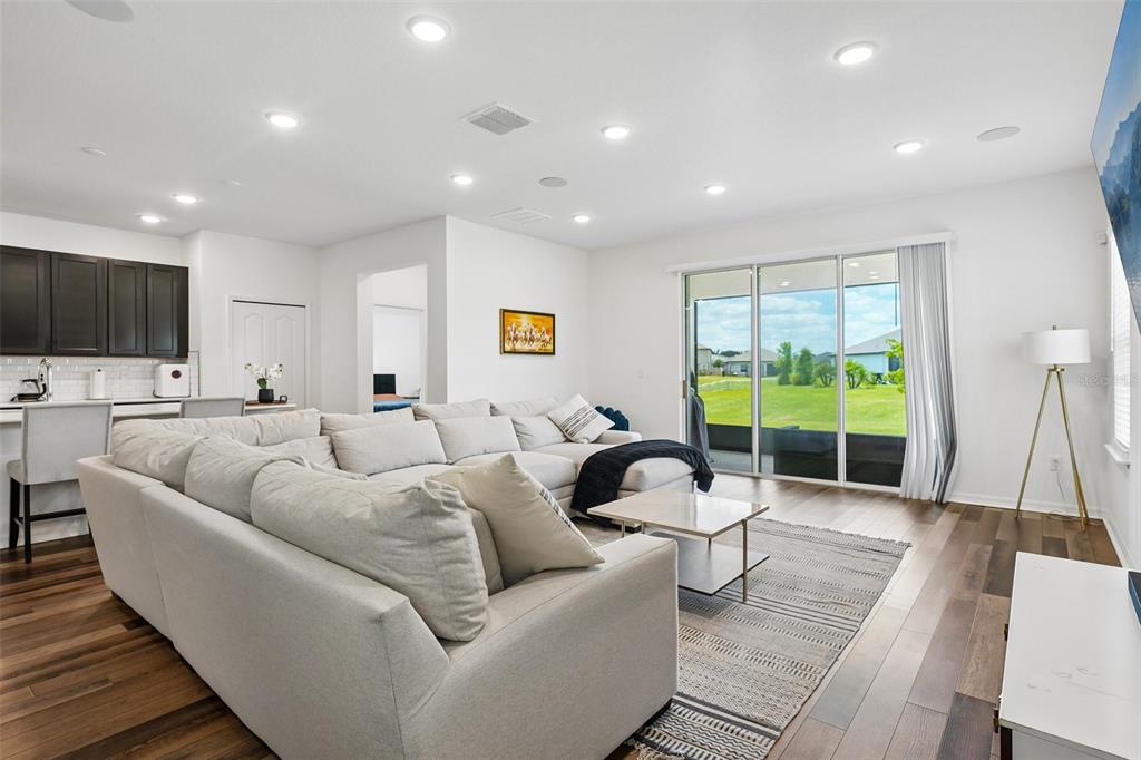 A living room with a large sectional sofa, wood floors, and sliding glass doors — 11225 JUNE BRIAR LOOP, SAN ANTONIO, FL