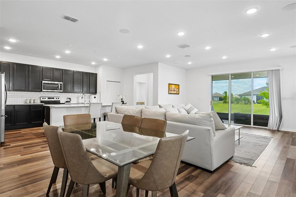 An open-concept living area features a kitchen with dark cabinets, a dining table, and sofa — 11225 JUNE BRIAR LOOP, SAN ANTONIO, FL