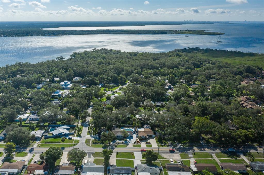 An aerial view shows a residential neighborhood with tree-lined streets near a large body of water — 2180 PHILIPPE PARKWAY, SAFETY HARBOR, FL