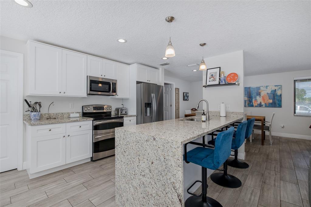 A kitchen features white cabinets, granite countertops, stainless steel appliances, and a breakfast bar — 2180 PHILIPPE PARKWAY, SAFETY HARBOR, FL