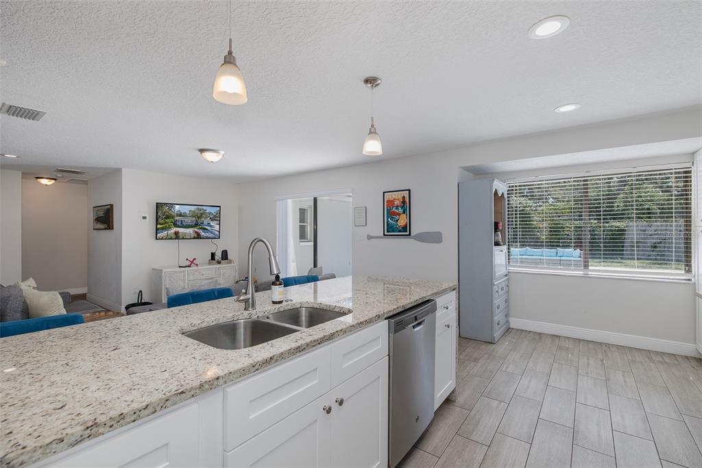 A kitchen island with a granite countertop and stainless steel sink faces a living area — 2180 PHILIPPE PARKWAY, SAFETY HARBOR, FL