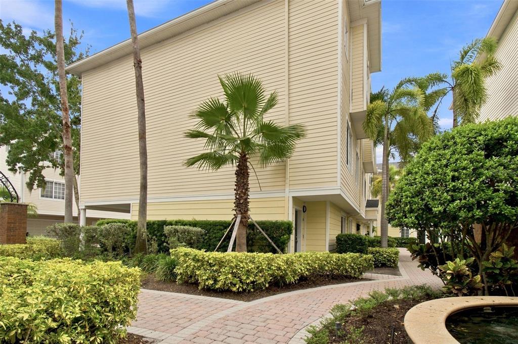 A multi-story beige building with a palm tree and a brick walkway in the foreground — 9801 MEADOW FIELD CIRCLE, TAMPA, FL