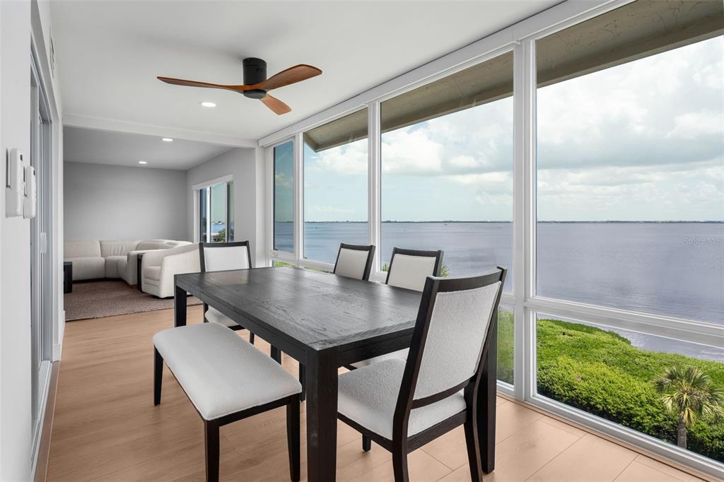 A dining area with a dark wood table and chairs overlooks a large body of water — 4800 GULF OF MEXICO DRIVE UNIT PH 3, LONGBOAT KEY, FL