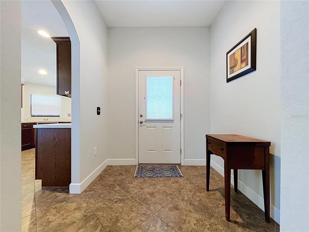An entryway features tile flooring, a white front door, and a wooden console table — 418 MAJESTIC GARDENS BLVD, WINTER HAVEN, FL