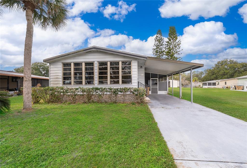 A single-story mobile home with a concrete driveway, carport, and a front lawn — 2733 CRANMOOR DRIVE, KISSIMMEE, FL