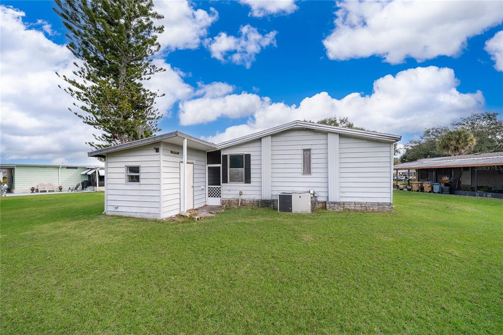 A light gray single-story mobile home with a small attached shed sits on a lawn — 2733 CRANMOOR DRIVE, KISSIMMEE, FL