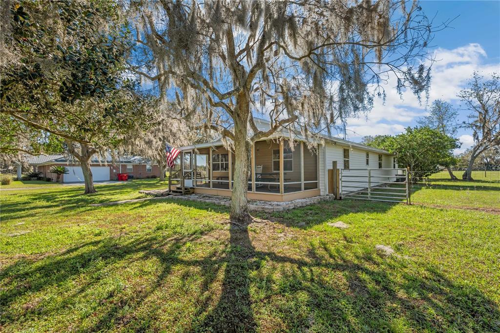 A single-story house with a screened-in porch stands in a grassy yard under large trees — 2615 CR 762, WEBSTER, FL