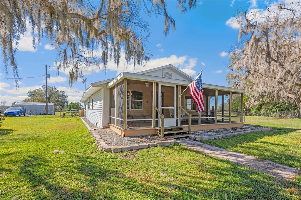A single-story house with a screened-in front porch and an American flag in a yard — 2615 CR 762, WEBSTER, FL