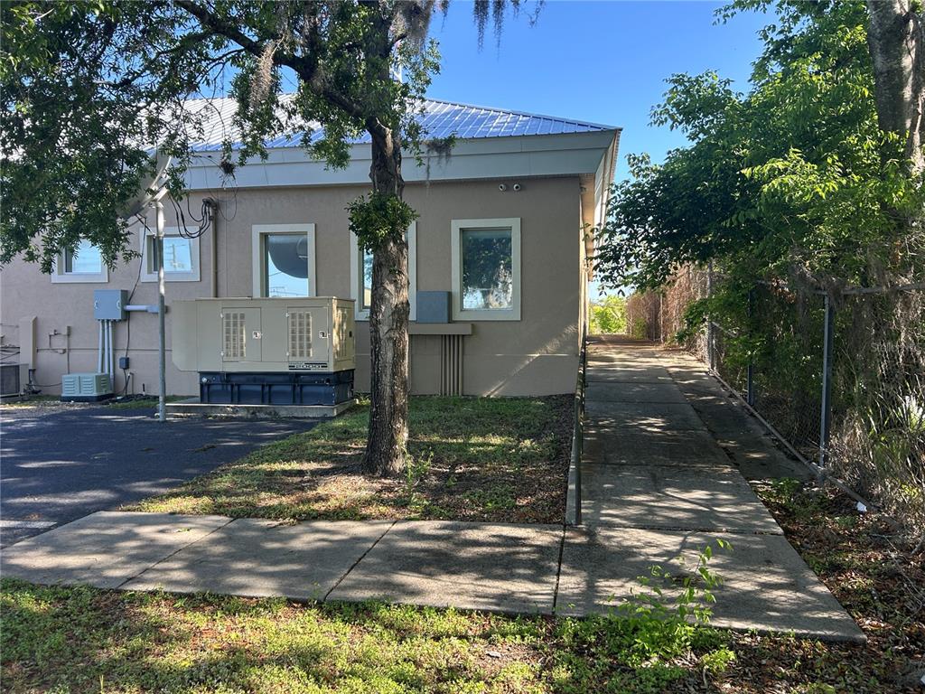 An exterior view of a building with a concrete ramp, a generator, and trees — 1137 SW 7TH ROAD, OCALA, FL