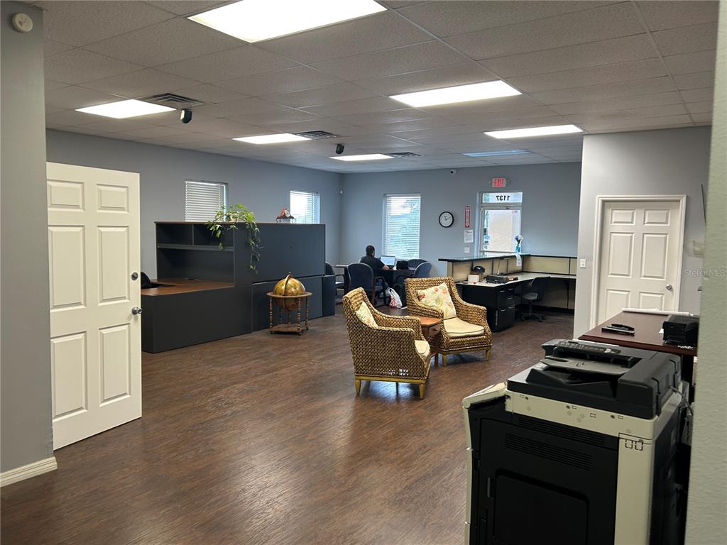 An office space features a reception area, wicker chairs, dark wood flooring, and cubicle desks — 1137 SW 7TH ROAD, OCALA, FL
