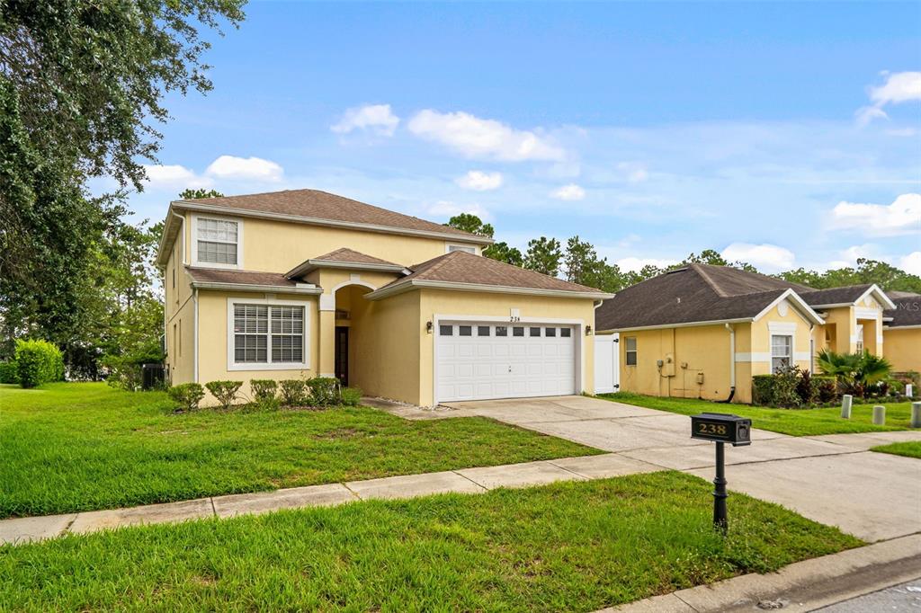 A two-story yellow house with a white garage and a brown shingled roof — 238 N HAMPTON DRIVE, DAVENPORT, FL
