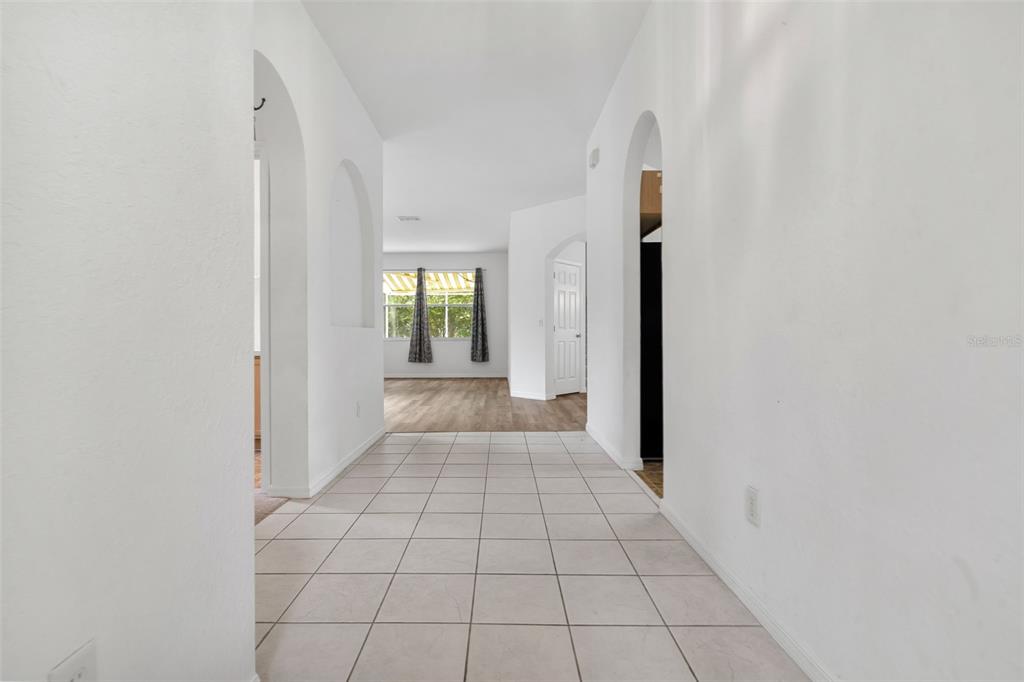 A tiled hallway leads to an open living area with wood-look flooring and a window — 238 N HAMPTON DRIVE, DAVENPORT, FL