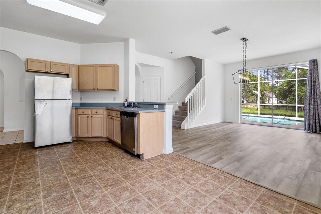 A kitchen with light wood cabinets and tile flooring transitions into a living area with wood-look floors — 238 N HAMPTON DRIVE, DAVENPORT, FL