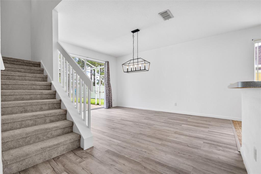 A dining area with wood-look flooring, a modern chandelier, and a carpeted staircase — 238 N HAMPTON DRIVE, DAVENPORT, FL