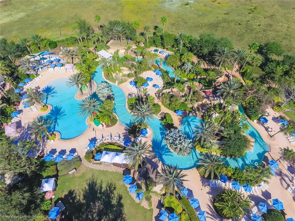 An aerial view of a resort-style swimming pool complex with palm trees and lounge chairs — 7622 EXCITEMENT DRIVE, REUNION, FL